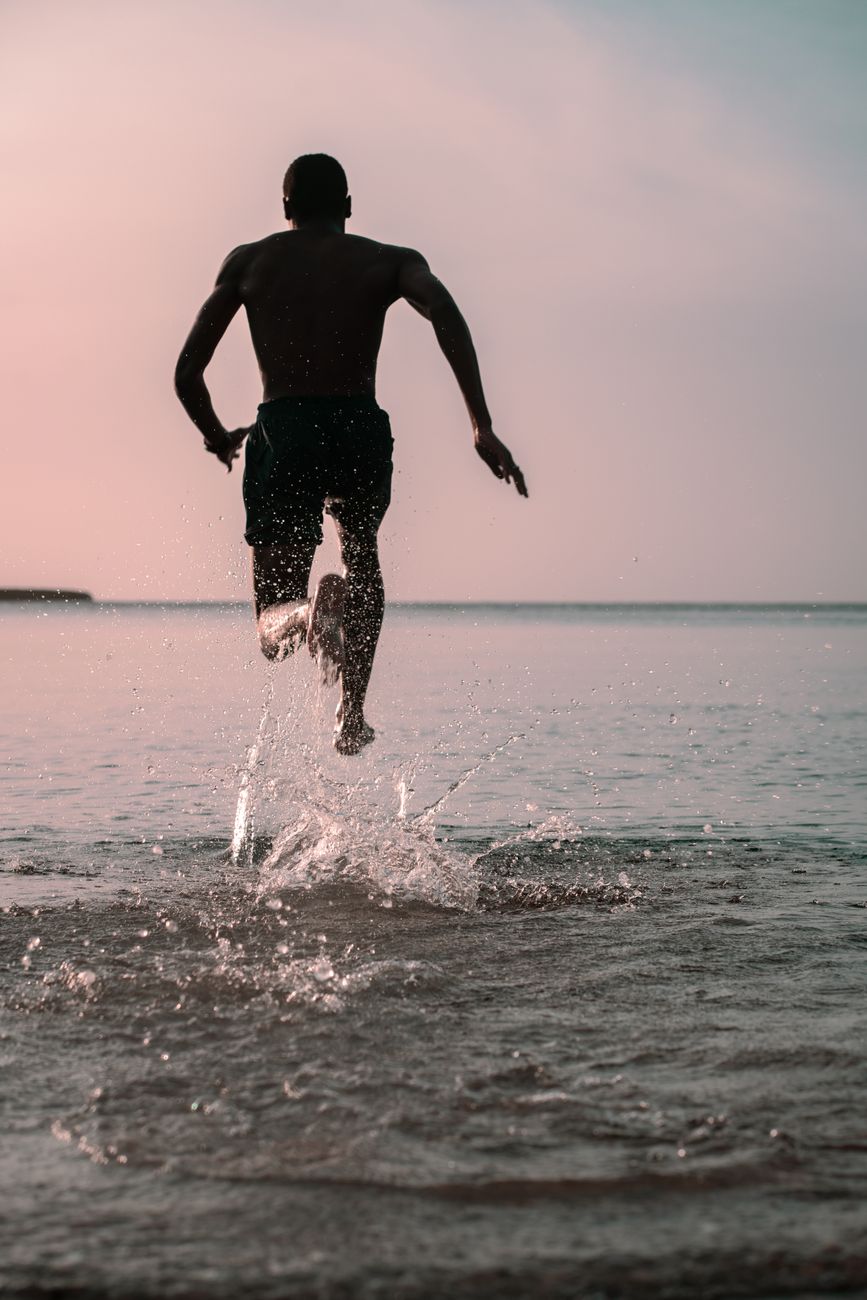 man in black shorts running on beach