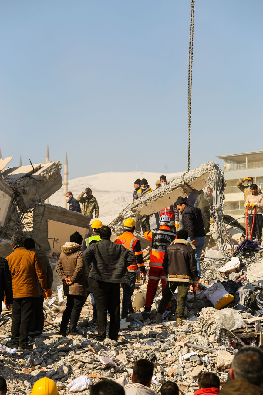 people gather around the rubble of a building